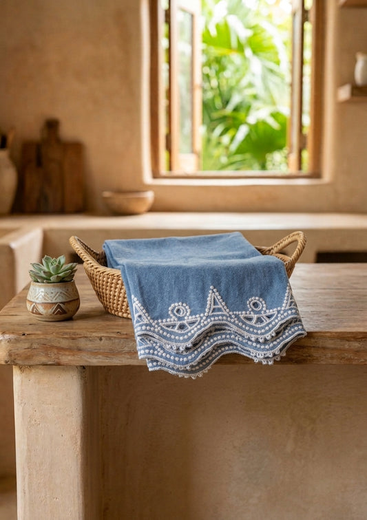 Heritage Stitch Dish Towel – chambray with white geometric border embroidery, styled in a wicker basket
